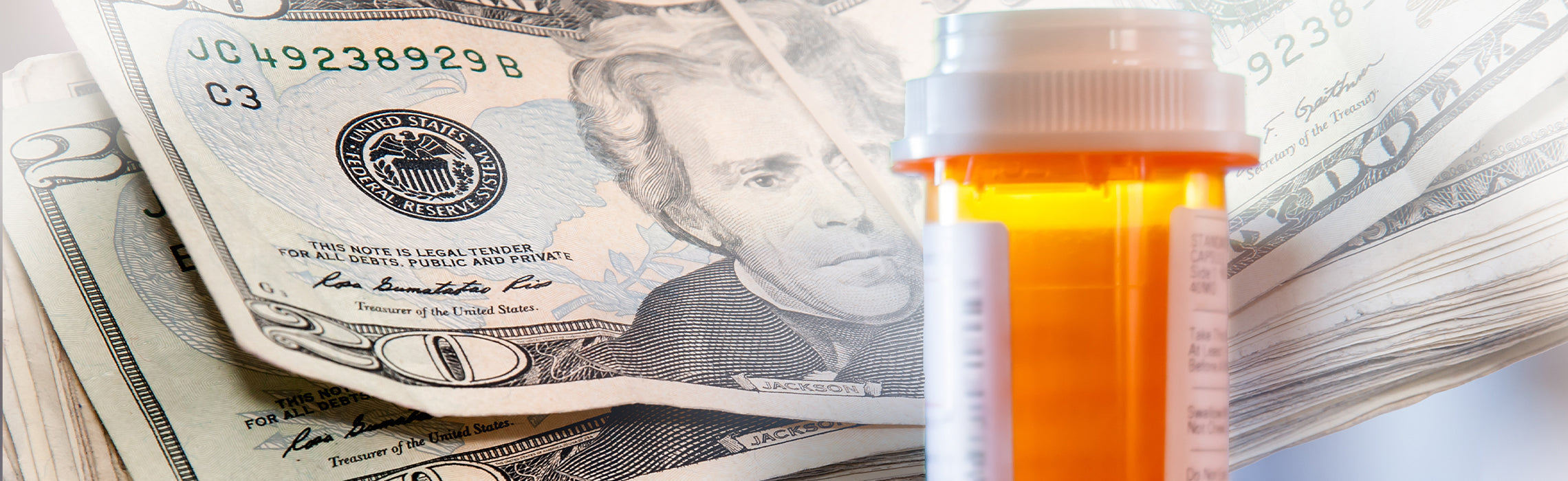 Close-up of a prescription pill bottle placed in front of stacked U.S. $20 bills, featuring Andrew Jackson’s portrait, representing healthcare costs, prescription expenses, and the financial burden of medical care.
