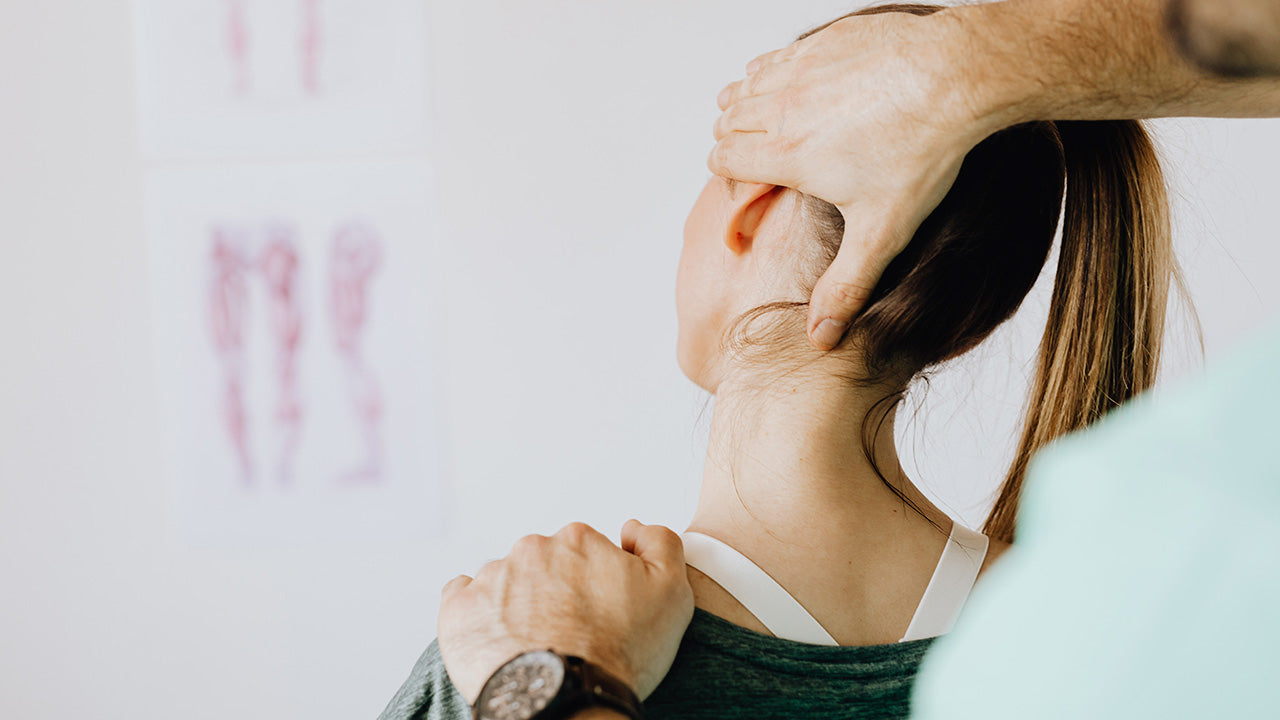 Close-up of a practitioner’s hands supporting a person’s head and shoulder while gently adjusting the neck in a clinical setting, illustrating neck pain treatment or chiropractic care. No visible text or branding.