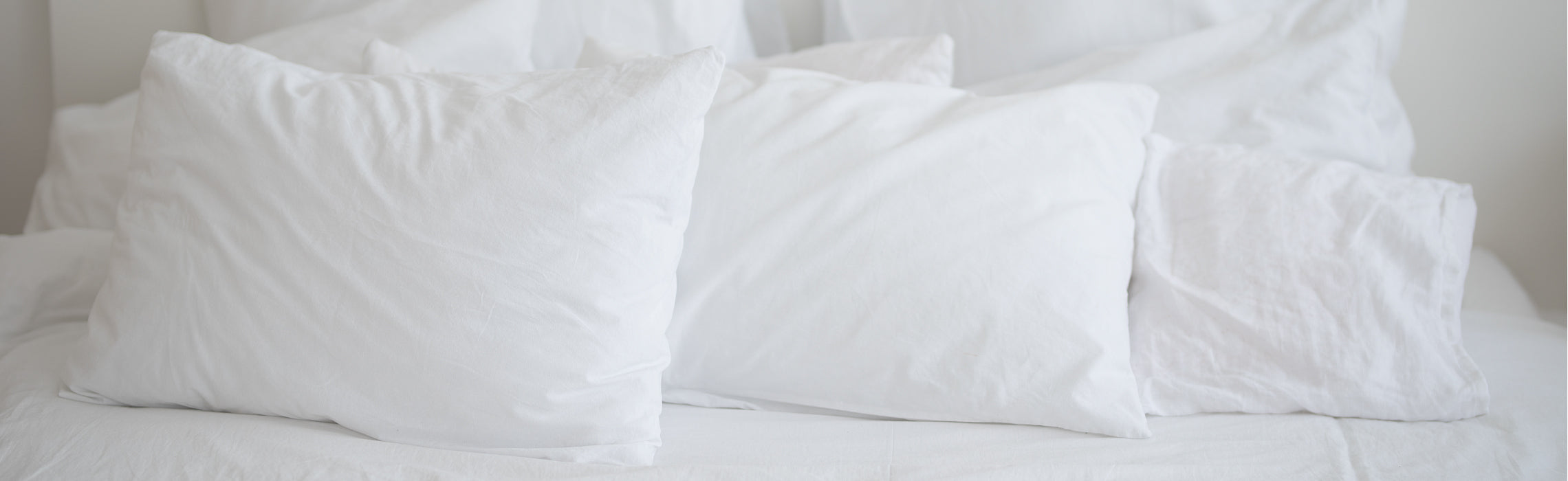 Three white pillows arranged on a neatly made bed with white bedding, representing sleep comfort, bedroom decor, and supportive pillows for restful sleep.