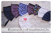 Assorted reusable cloth face masks in various colors and patterns arranged on a wooden surface, with text “#SpreadKindnessMasksOn.”