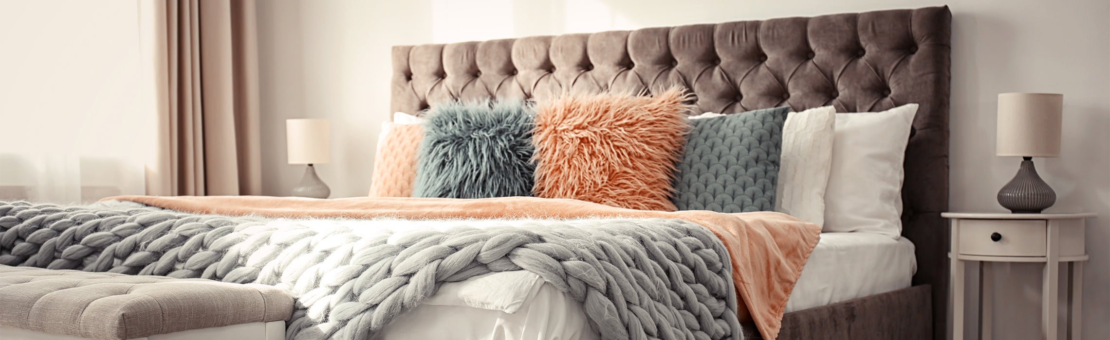 Stylish bedroom featuring a tufted upholstered headboard, layered bedding, decorative throw pillows, and soft neutral décor.