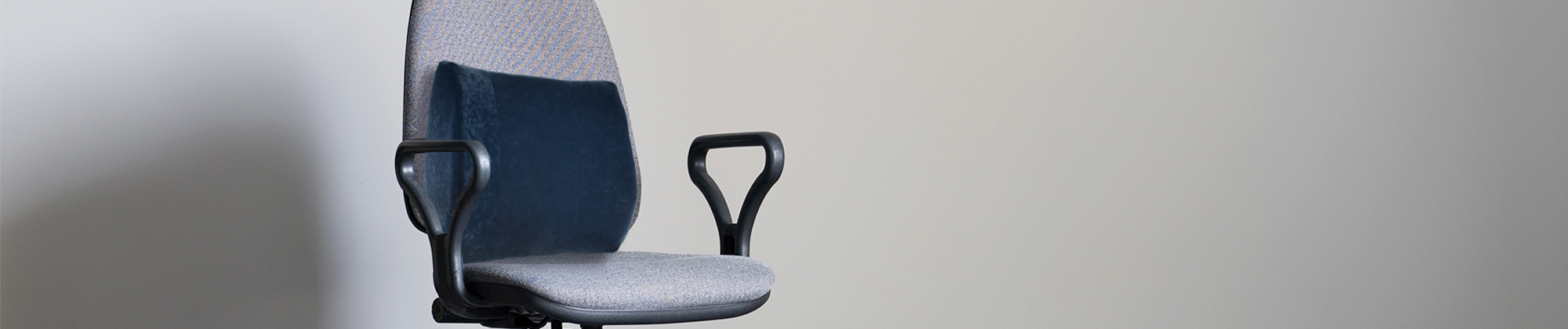 Core Products lumbar support cushion attached to a chair with adjustable straps and contoured padding; no visible text, highlighting ergonomic back support, improved posture, and seated comfort.