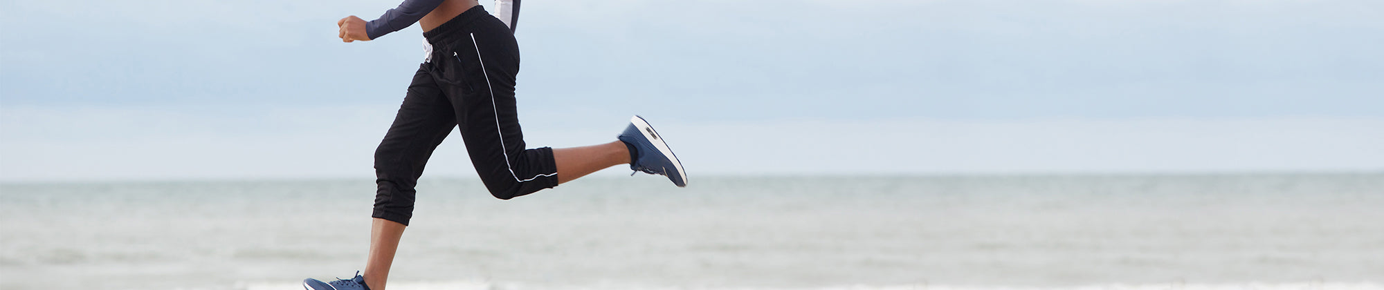 Active lifestyle banner featuring a person running along the beach shoreline; no visible text, highlighting movement, endurance, and overall health and wellness.