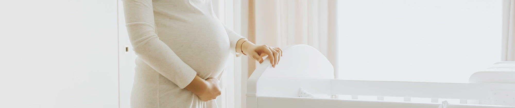 maternity support lifestyle banner featuring a pregnant woman gently holding her belly indoors; no visible text, highlighting comfort, support, and wellness during pregnancy.