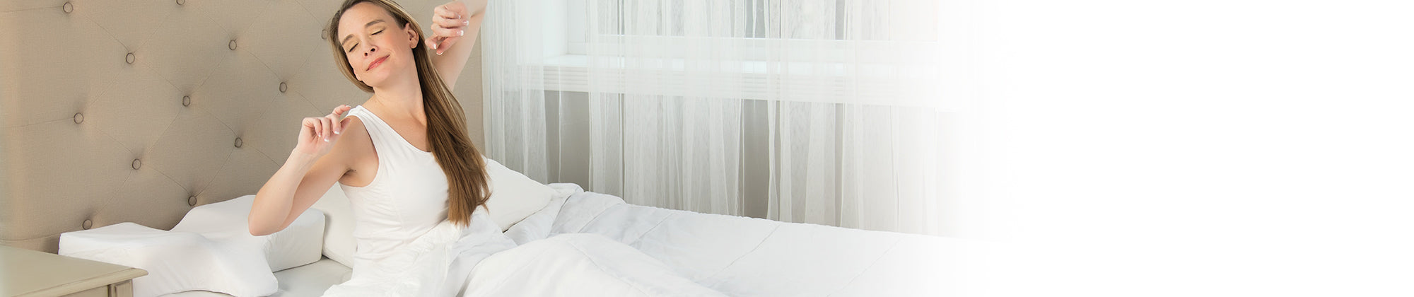 Therapeutica cervical support pillow shown on a bed with a woman stretching comfortably in white bedding, demonstrating proper neck alignment and restful sleep; contoured foam pillow supports head and neck for pain relief and improved posture.
