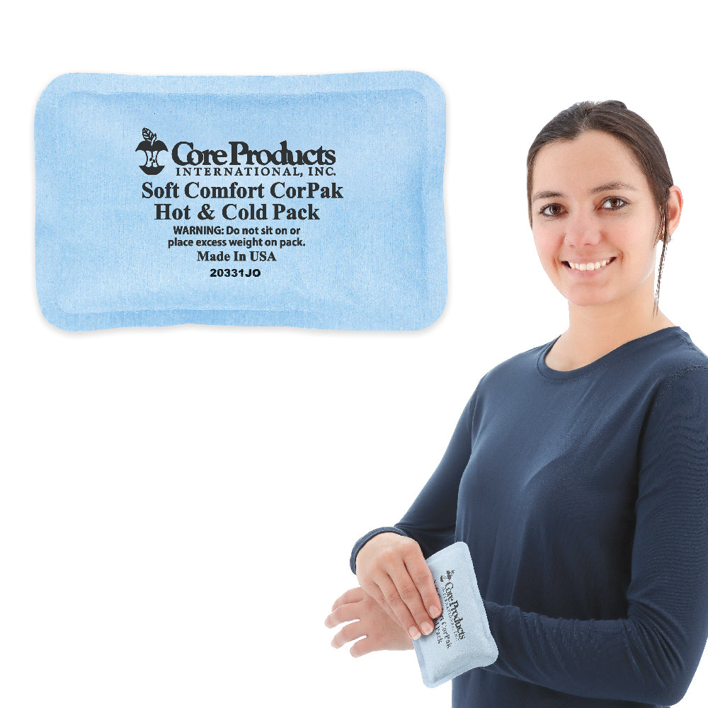 Core Products® Soft Comfort CorPak® Small hot and cold therapy pack in blue, shown with printed text: “Core Products International, Inc Soft Comfort CorPak Hot & Cold Pack WARNING: Do not sit on or place excess weight on pack. Made in USA.” A woman holds the compact pack against her wrist, demonstrating targeted pain relief and convenient use
