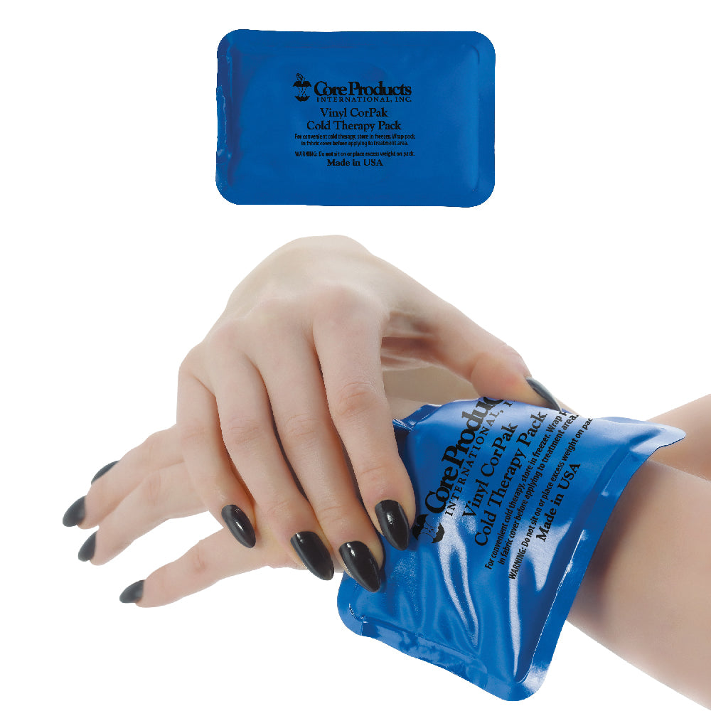Core Products® Vinyl CorPak® Cold Therapy Pack in a small rectangular size, shown applied to the wrist for localized cold therapy. The flexible blue vinyl pack conforms comfortably to the hand and wrist, helping reduce pain, swelling, and inflammation. Includes product branding and “Made in USA” printed on the pack.