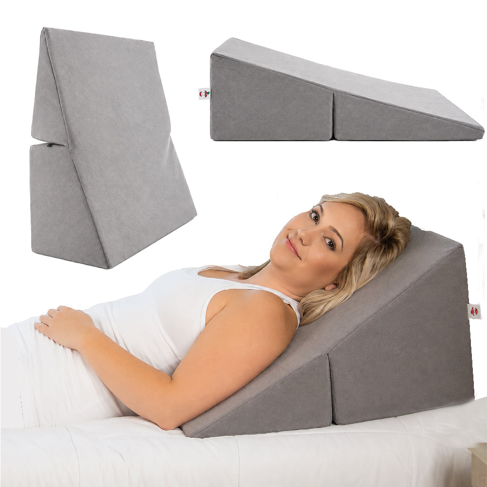 Core Products Bed Wedge Positioning Support Pillow shown in gray in upright, flat wedge, and reclining positions. A woman rests on the contoured wedge pillow with her upper body elevated while lying in bed. The foldable design provides versatile positioning for back and torso support, relaxation, reading, sleeping, and elevated comfort.