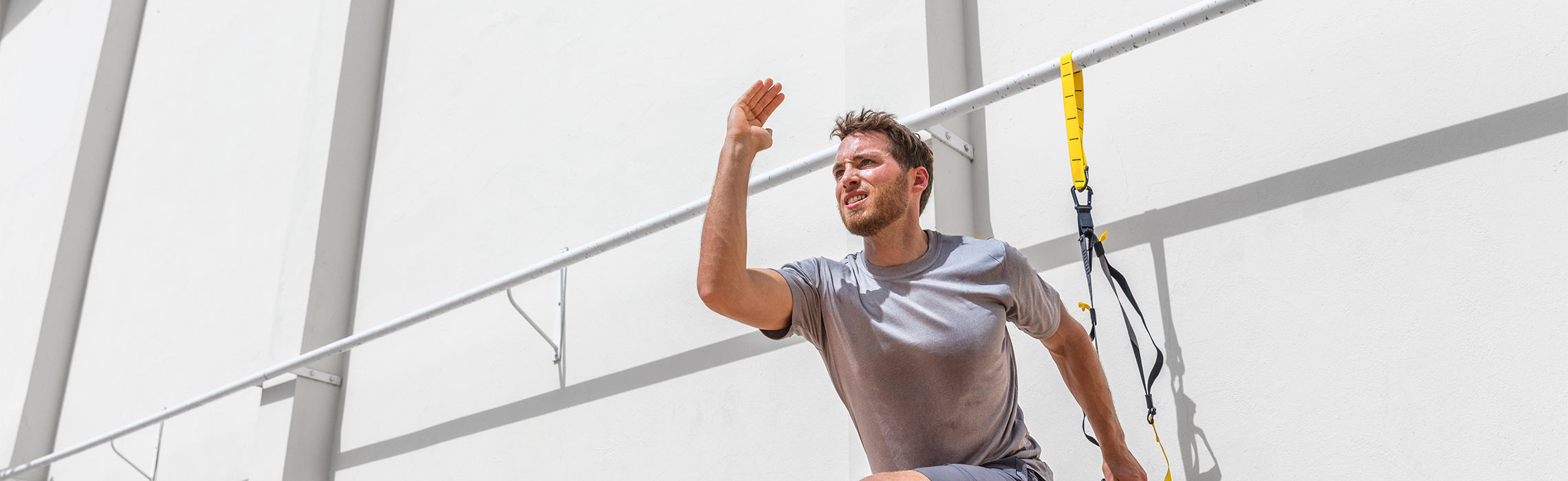 Athletic man exercising with suspension training straps in a modern gym