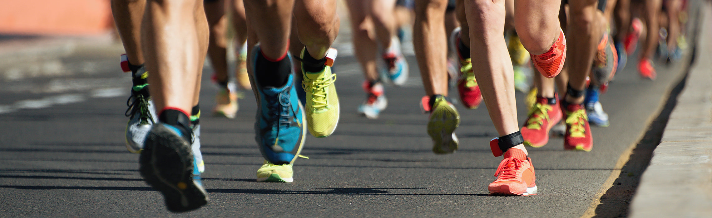 Close-up of runners’ legs and colorful athletic shoes during a road race or marathon event.