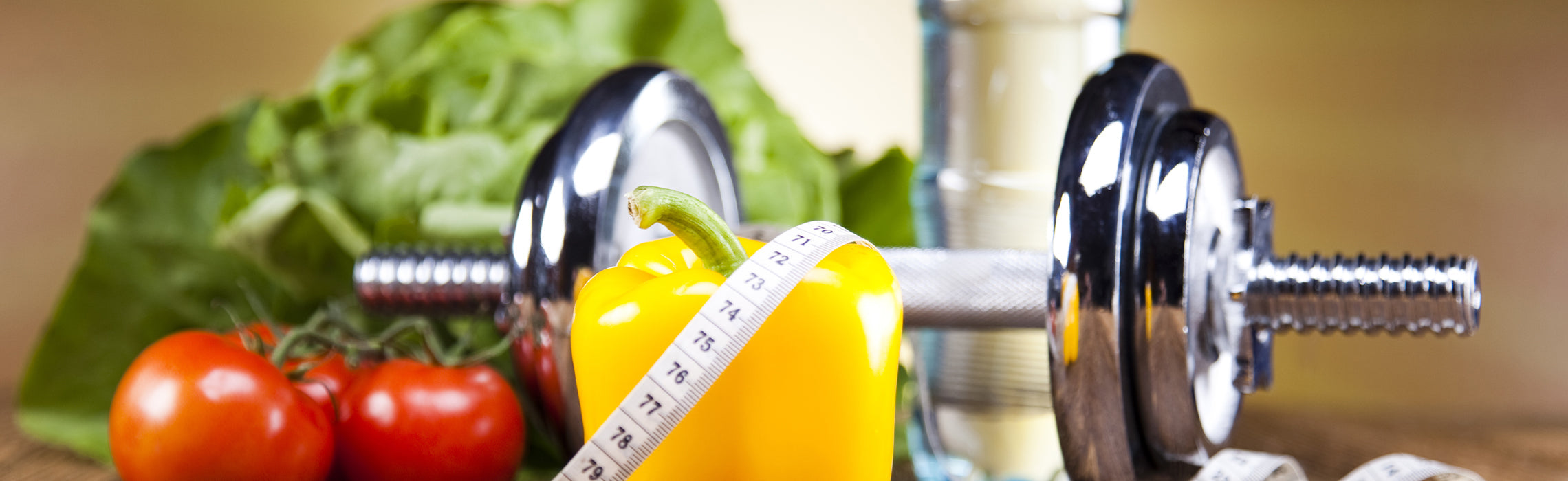 Dumbbells, fresh vegetables, and a measuring tape arranged together to represent fitness & healthy eating