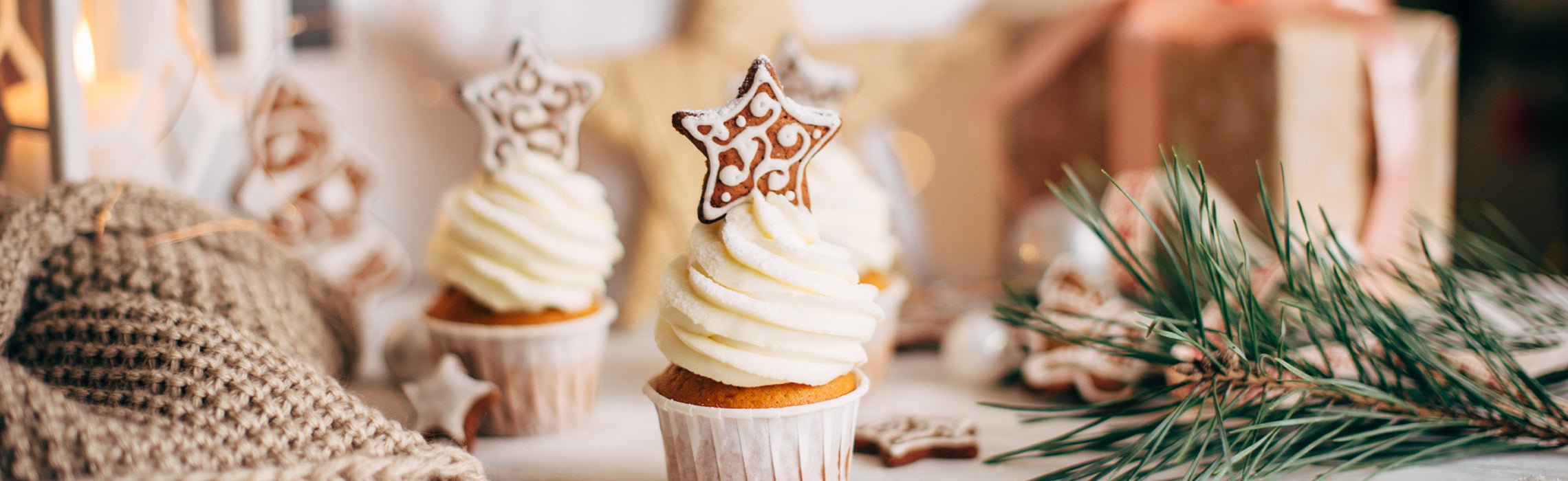 Festive cupcakes topped with white frosting and star-shaped cookie decorations on a table with pine branches and holiday decor, representing Christmas desserts, baking, and seasonal celebration.