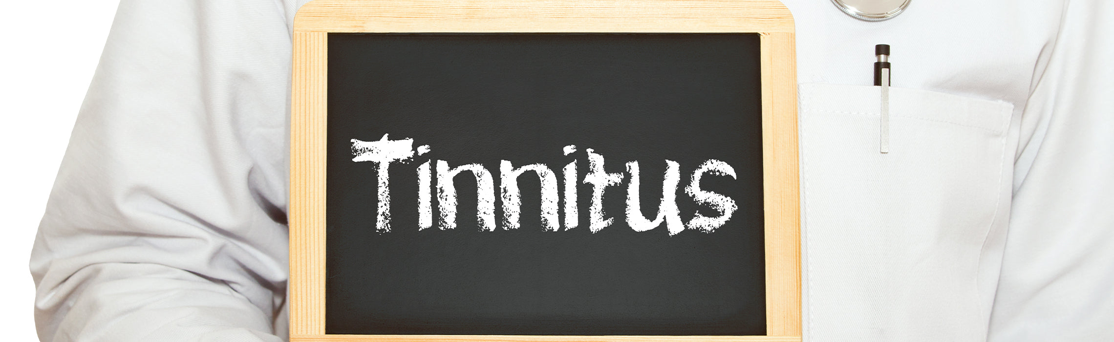 Chalkboard with the word “Tinnitus” written in white lettering, held against a white medical uniform with a pen in the pocket, representing hearing health and ear-related conditions.