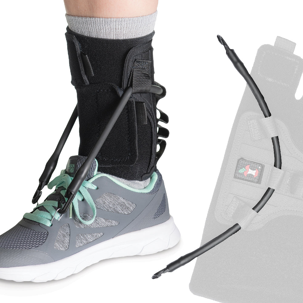 Core Products FootFlexor Orthosis shown worn over a sock with an athletic shoe. The black ankle support features adjustable straps and flexible cords extending from the brace to the shoe to assist foot positioning. A faded side view highlights the cord routing and Core Products logo. Designed to provide dynamic foot and ankle support during walking and everyday mobility.