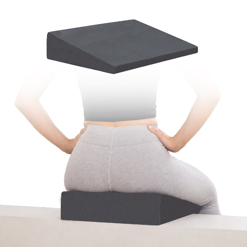 Core Products Stress Relief Wedge with Firm foam seating cushion shown alone and beneath a seated person to demonstrate positioning and support. The dark gray wedge-shaped cushion provides an angled seating surface designed to encourage proper posture, pelvic positioning, and comfortable spinal alignment while sitting. No visible text appears in the image.